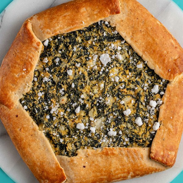 A hexagonal spinach and feta galette with a thick folded over crust around the edges.