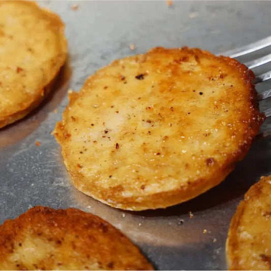 Crispy golden-brown fried Daring Plant-Based Unbreaded Gluten-Free Chicken Patties cooking on a metal pan, with one slice being lifted by a metal spatula.