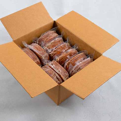 An open cardboard box with individually sealed packs of Tofurky Next Gen Smoked Ham Deli Slices
