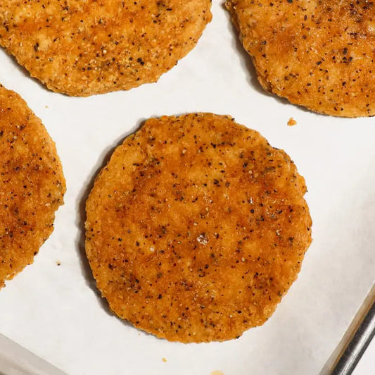 Four cooked Daring Plant-Based Breaded Chicken Patties on a white baking sheet lined with parchment paper.