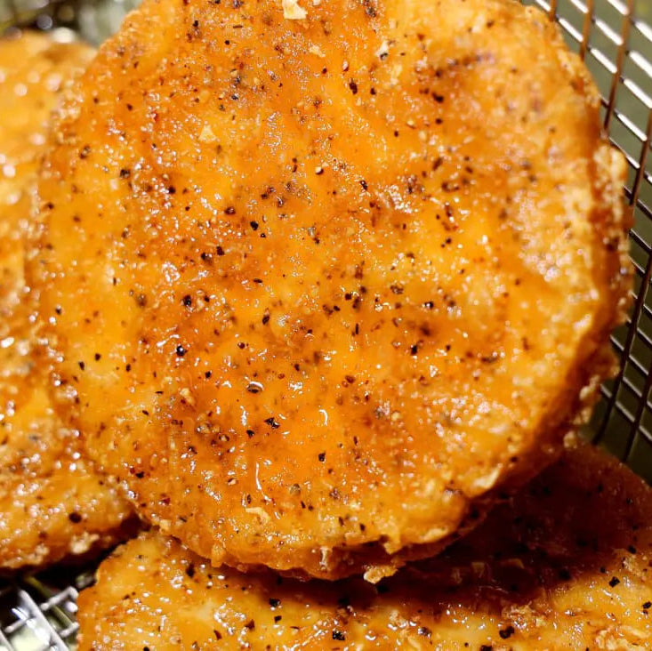 Three golden-brown fried Daring Plant-Based Breaded Chicken Patties sitting in a metal fry basket.