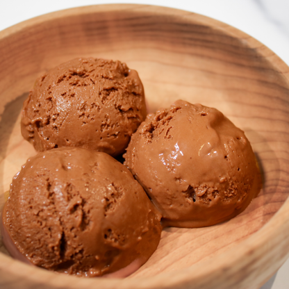 Three scoops of Rose City Creamery chocolate ice cream in a light brown wooden bowl.