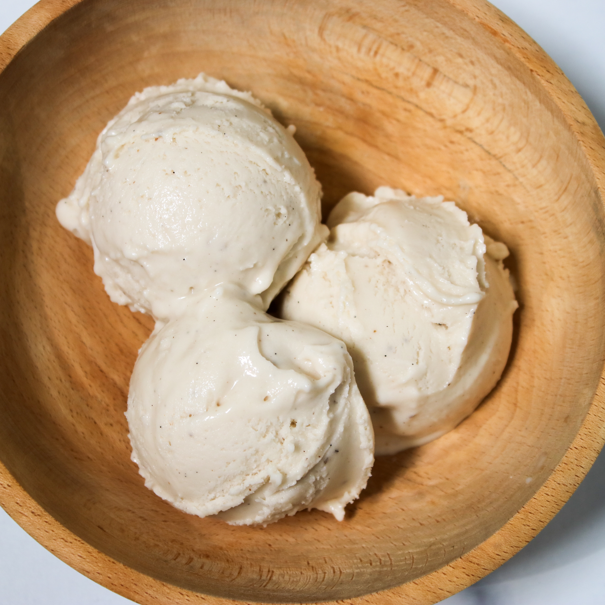 Three scoops of Rose City Creamery Tahitian Vanilla ice cream in a light brown wooden bowl.