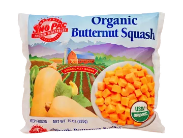 A bag of Sno Pac Organic Butternut Squash, featuring a colorful illustration of a farm landscape and a bowl of cubed squash on the front packaging.