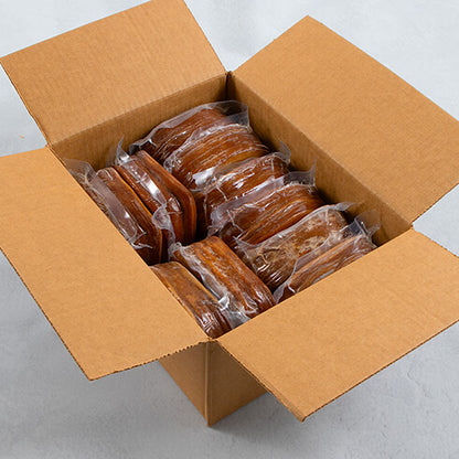 An open brown cardboard box filled with multiple individually wrapped packs of Tofurky Roasted Turk'y deli slices, photographed from above on a light gray surface.