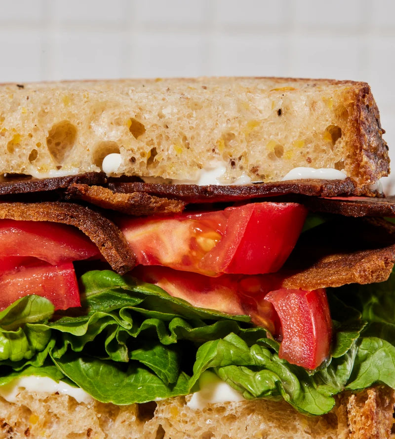 A closeup of a BLT sandwich with Prime Roots bacon, tomato, lettuce, and mayonnaise.