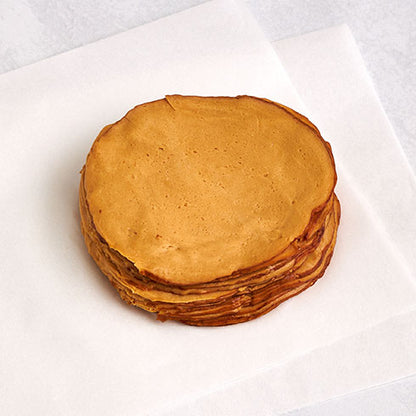 A stack of  Tofurky Hickory Smoked Deli Slices on a white sheet of parchment paper